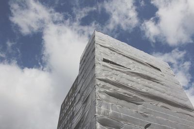 Low angle view of modern building against cloudy sky