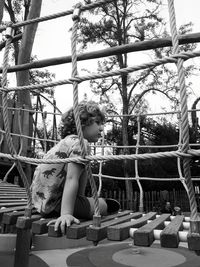 Full length of girl sitting on railing against trees