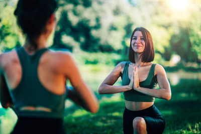 Women doing yoga by the lake