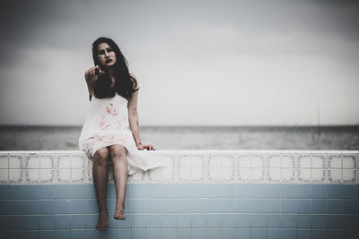 Portrait of young woman standing against sea