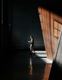 Side view of woman walking in corridor of building