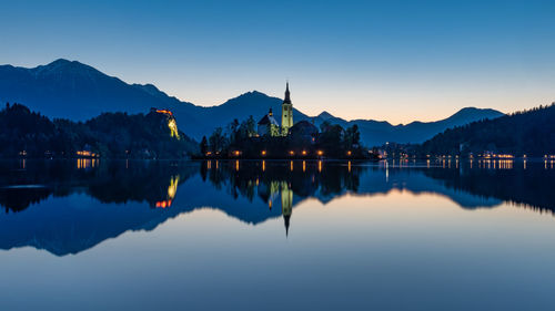 Reflection of church in lake against sky during sunset