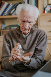 Senior man using hand sanitizer at home