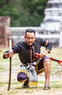 Full length of warrior crouching against old building