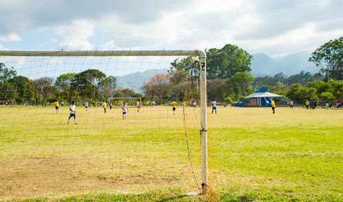 Men playing soccer on field against sky