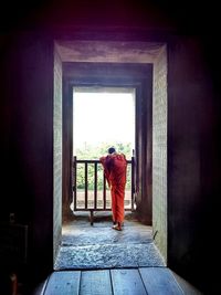 Rear view of woman looking through window of building