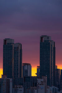 Skyscrapers in city against sky during sunset