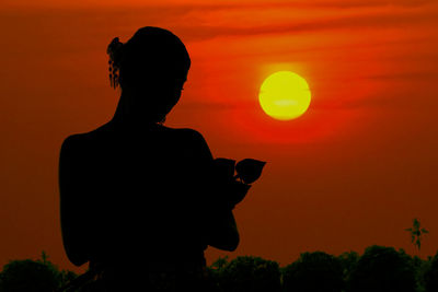 Silhouette man standing against orange sunset sky