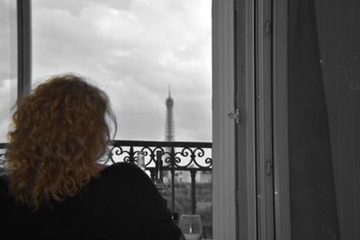 Rear view of woman looking through window