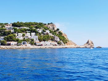 Buildings by sea against blue sky