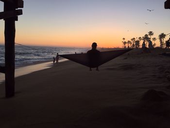 Silhouette of people at beach during sunset