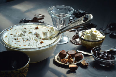 High angle view of ice cream in bowls with peanut butter cupcakes and chocolates on table