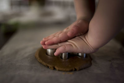 Cropped image of boy cutting dough with pastry cutter on table at home during christmas