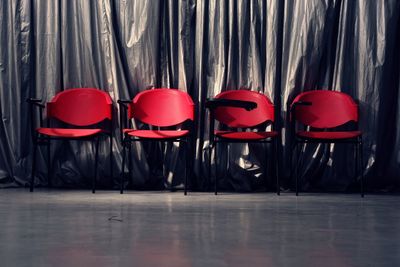 Empty red chairs against curtain on floor