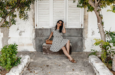 Portrait of young woman sitting on stone bench. summer, lifestyle, dress, fashion.