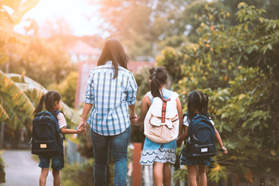 Rear view of girls with backpacks standing outdoors