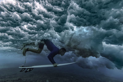 Male surfer with surfboard undersea during vacation at maldives