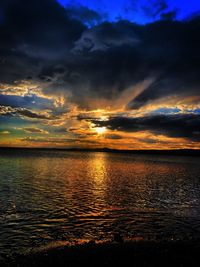 Scenic view of sea against dramatic sky during sunset