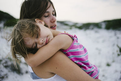 Mother carrying daughter sleeping at beach