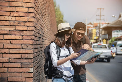 Couple reading map while standing by road on footpath