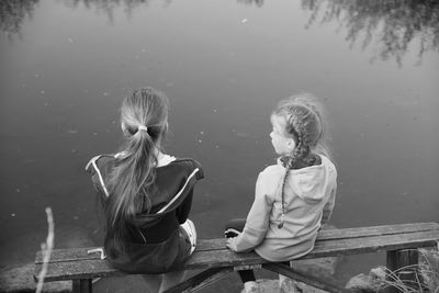 Rear view of women sitting by lake