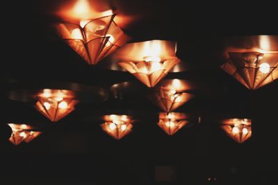 Close-up of illuminated light bulb hanging in the dark