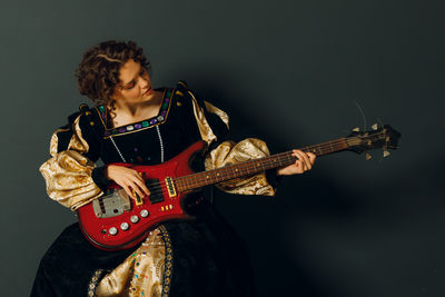 Portrait of man playing guitar against black background