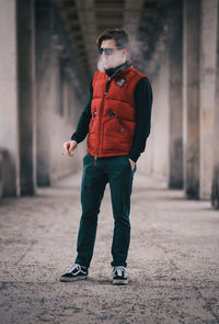 Full length of young man smoking while standing in corridor
