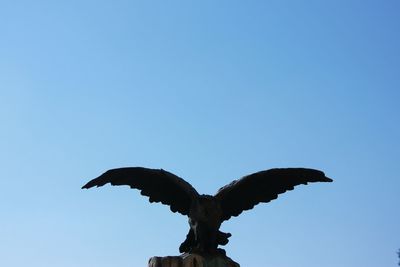 Low angle view of eagle statue against clear blue sky