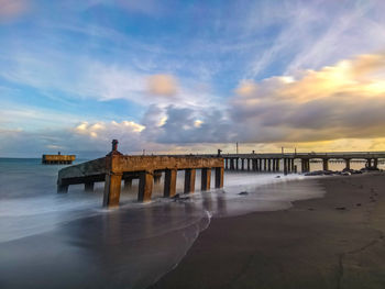 Pier over sea against sky during sunset