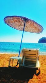 Chair on beach against clear sky