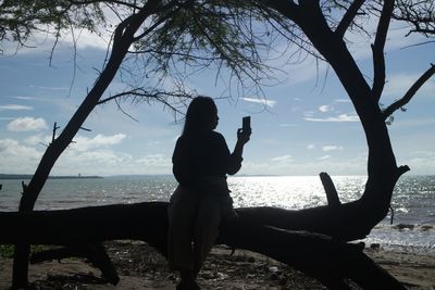 Rear view of woman photographing on beach