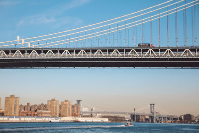 Low angle view of suspension bridge over river in city