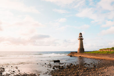Lighthouse by sea against sky