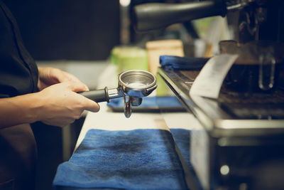 A female barista is holding coffee filter holder.