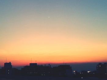 Silhouette cityscape against clear sky during sunset