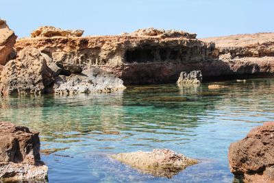 Rock formations in sea against clear sky