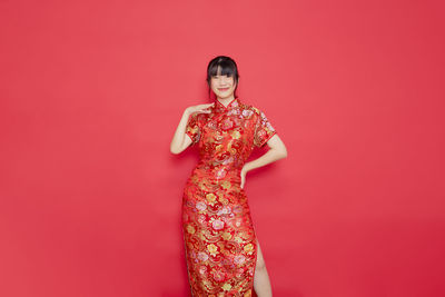 Portrait of woman standing against red background