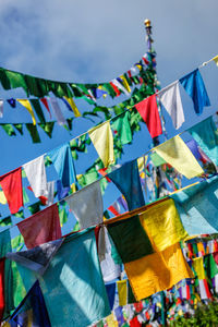 Low angle view of multi colored flags hanging against sky