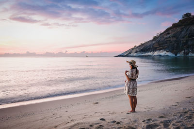 Rear view of man standing on beach during sunset