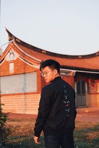 Full length of young man standing against house