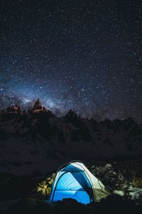 Tent against mountain range at night