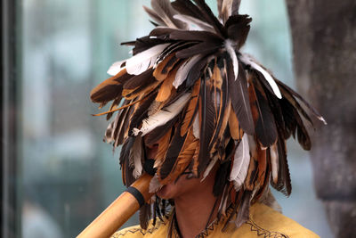 Close-up of man wearing feather headwear while playing musical instrument