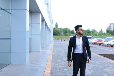 Young businessman standing against building