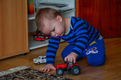 Boy playing with toy car on hardwood floor