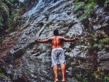 Rear view of shirtless man standing on rock