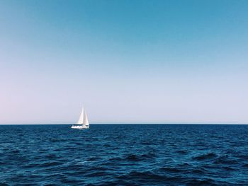 Sailboat in sea against clear sky