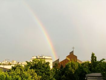 Rainbow over buildings in city against sky