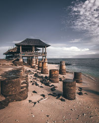 Built structure on beach by sea against sky