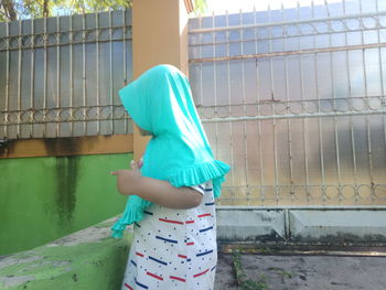 Rear view of woman standing against wall